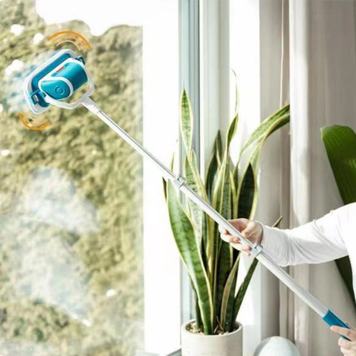 Electric scrubber on an extension pole cleaning a high window above a houseplant